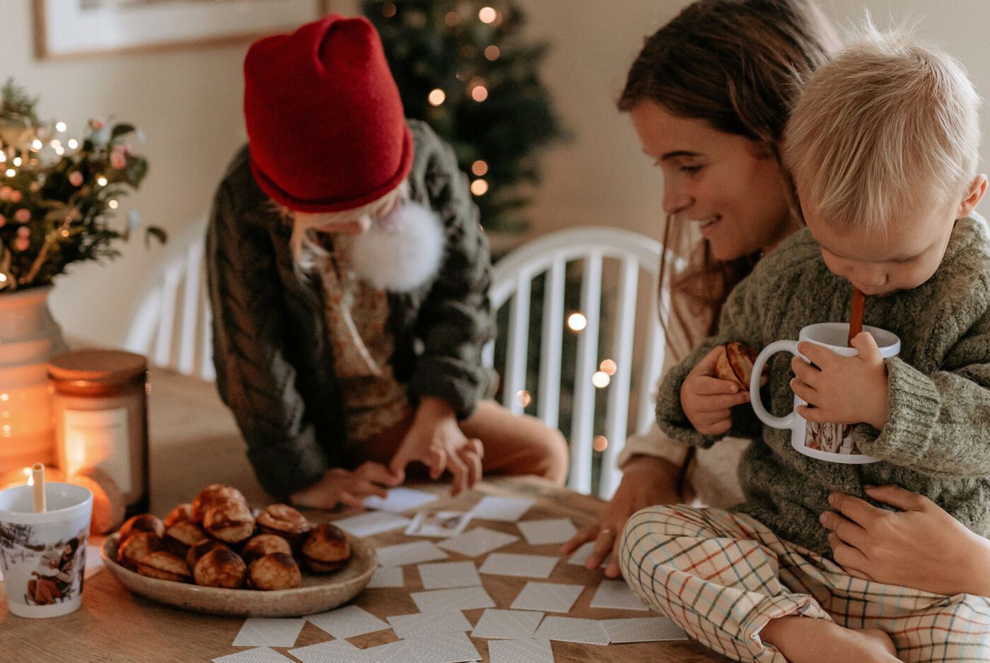 En familj skapar tillsammans ett kreativt projekt vid bordet med pepparkakor och julstämning.