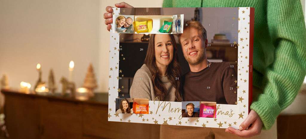 En adventskalender med bilder och godis, hålls av en person.