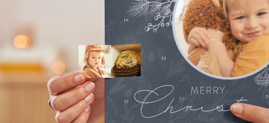 En person håller en CEWE fotokalender med kärleksfulla bilder och juldesign.