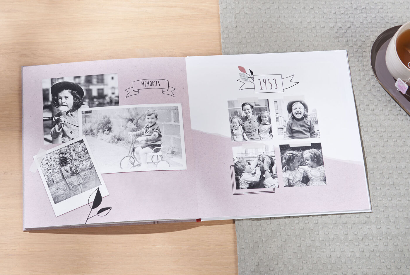 Ett öppet CEWE FOTOBOOK visar nostalgiska svart-vita bilder från familjeresor.